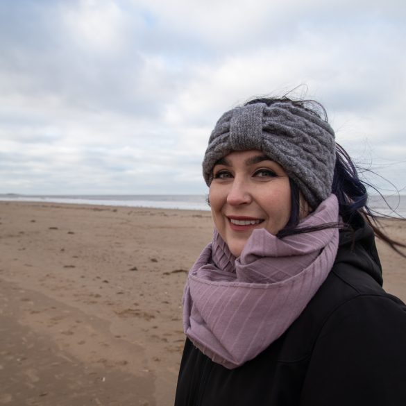 woman on beach smiling wearing purple scrarf and grey headband