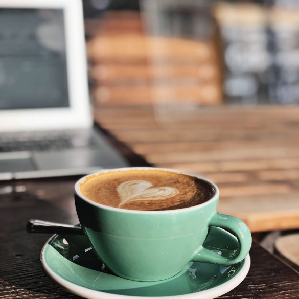 cup of coffee with laptop in background